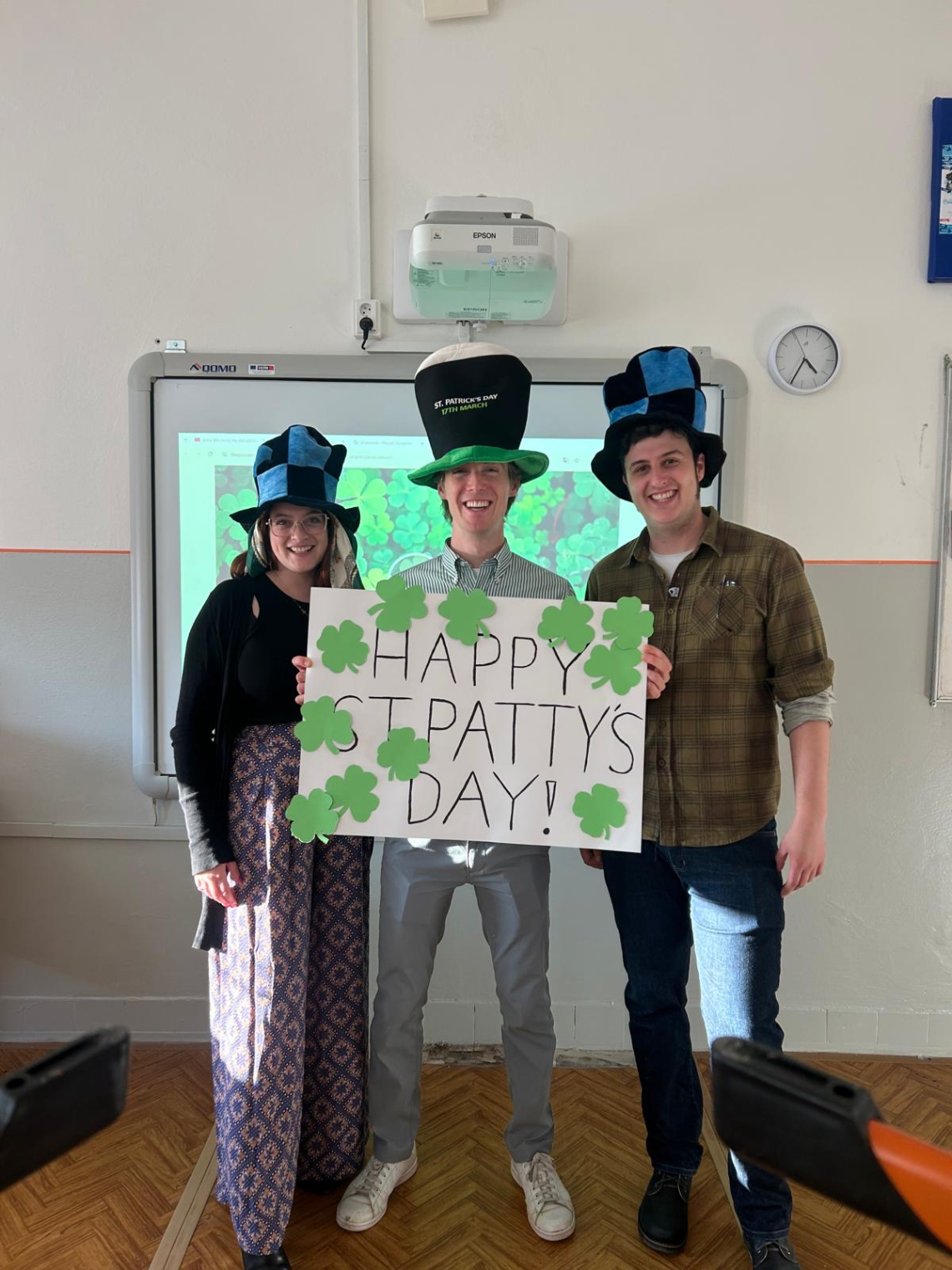 ETA holding a Happy St. Patty's Day sign in classroom