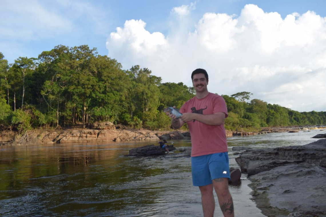 Grantee holding a fish next to a river